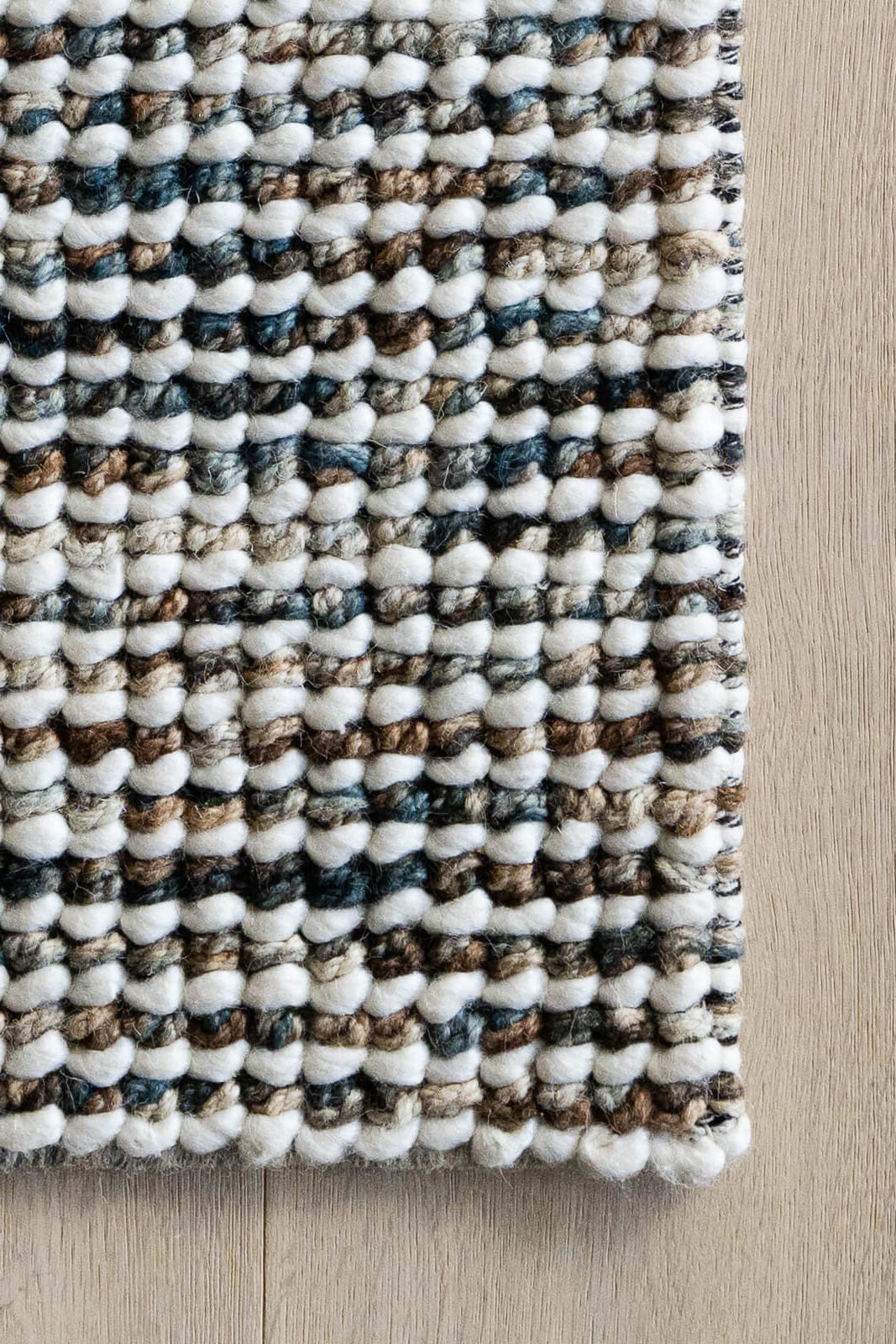 Jeffrey Peacock hand woven wool rug with textured loop pile in rich blue beige tones. Available in Belrose