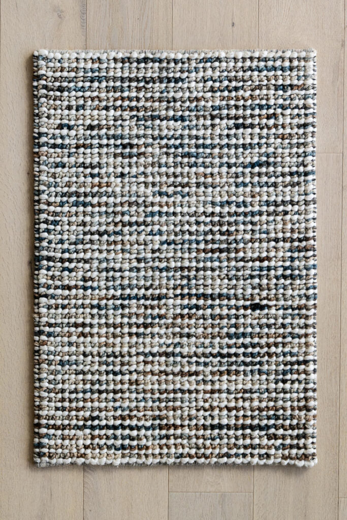 Jeffrey Peacock hand woven wool rug with textured loop pile in rich blue beige tones. Available in Belrose